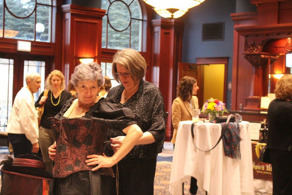 An event attendee getting fitted in a corset