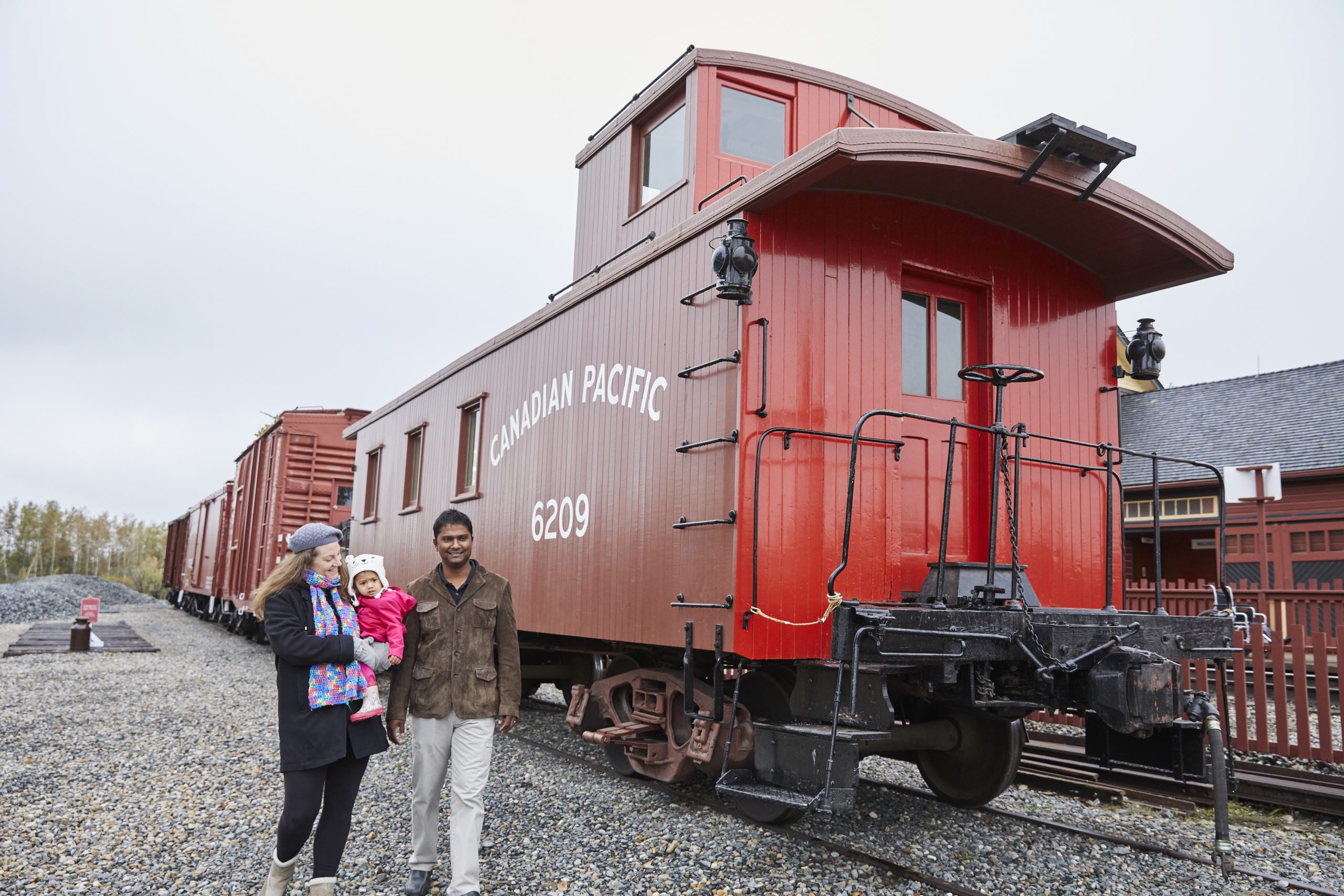 A family walking past CPR Caboose #6209 at Heritage Park