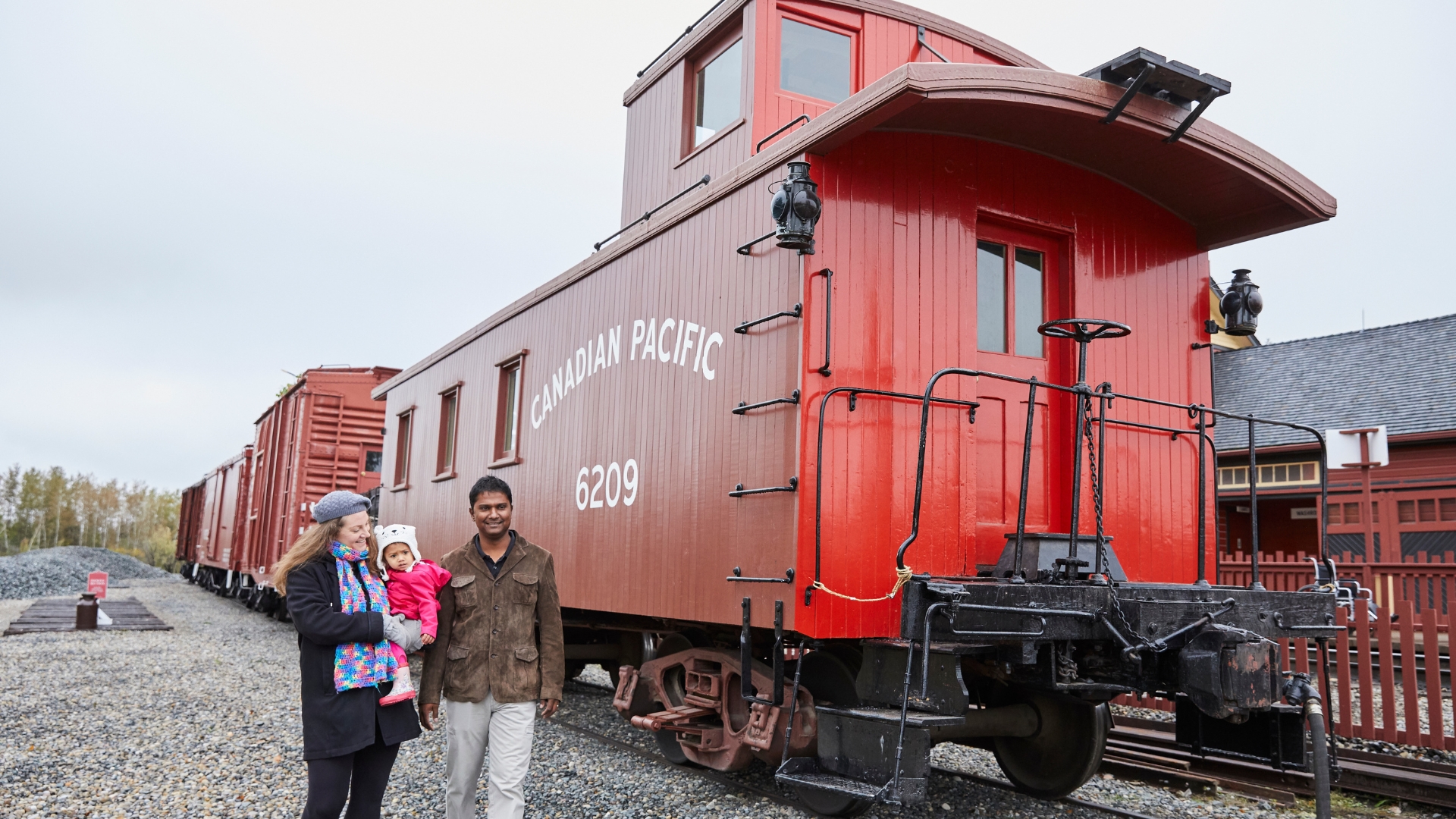 A family walking past CPR Caboose #6209 at Railway Days Heritage Park