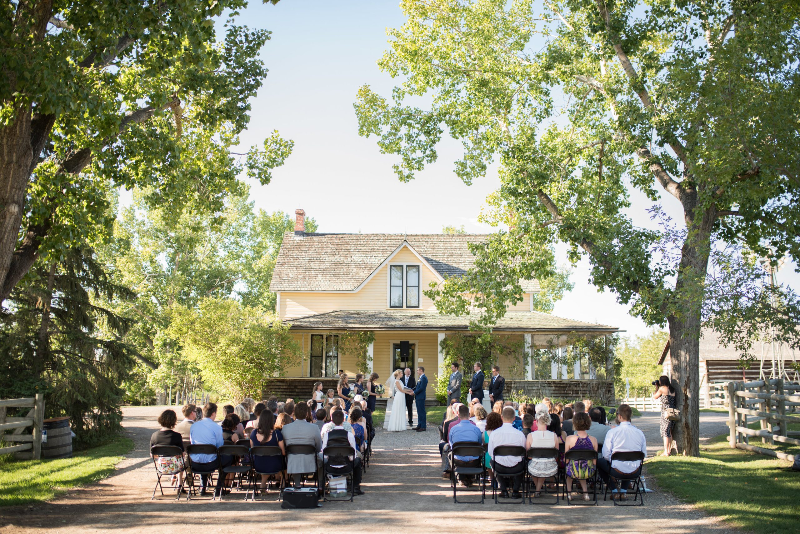 A wedding happening outside of a yellow ranch house