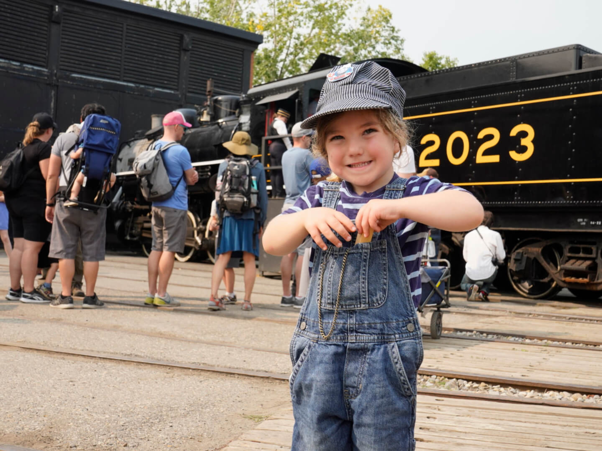 A little boy wears a train conductor outfit at Heritage Park