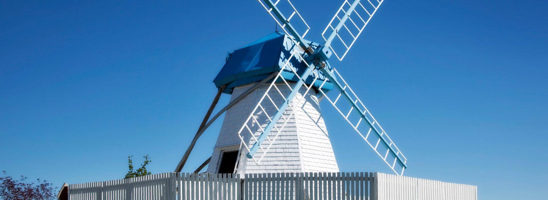 White and blue windmill with clear sky in background
