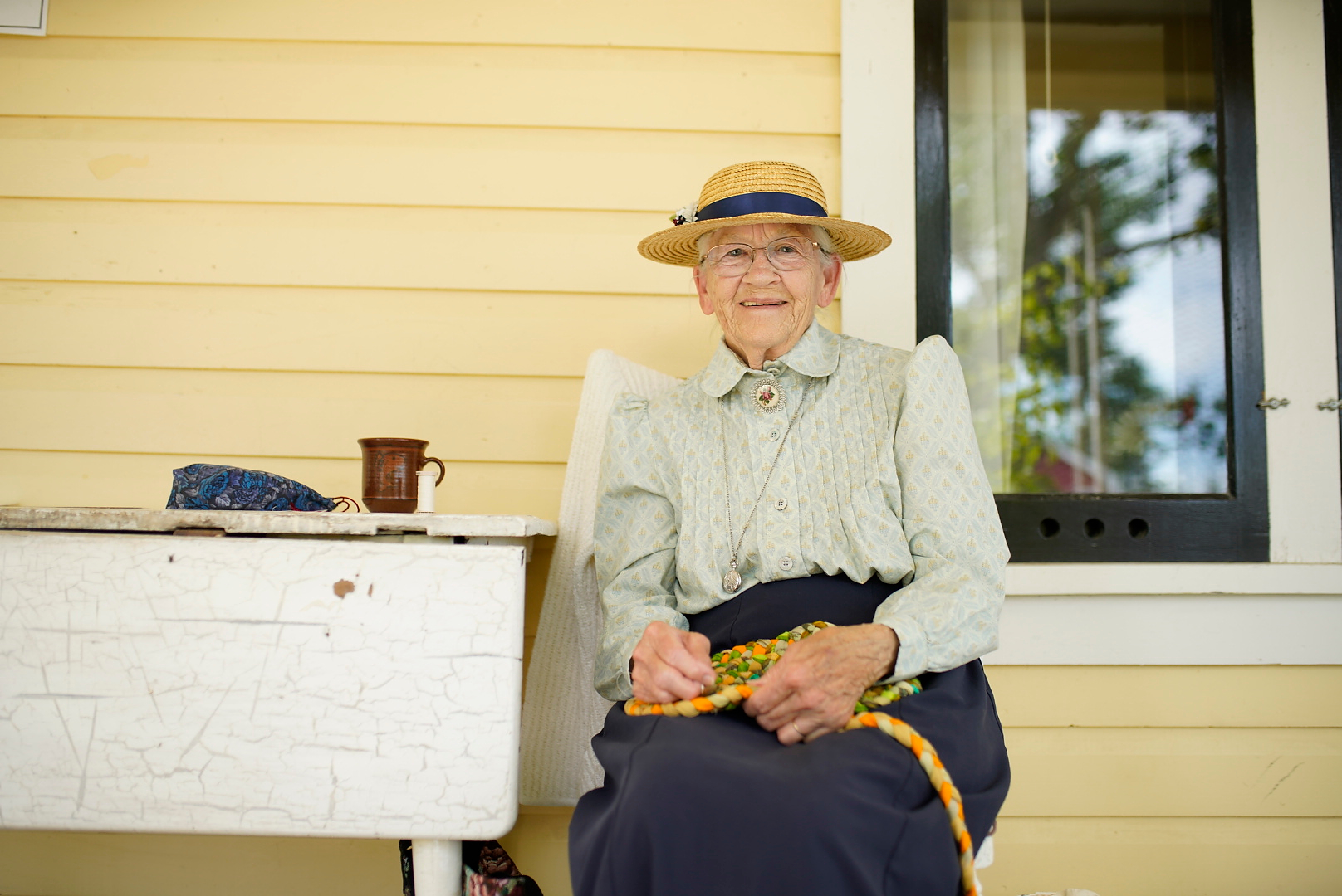 Heritage Park Volunteer - an older woman sitting on the porch of the ranch house