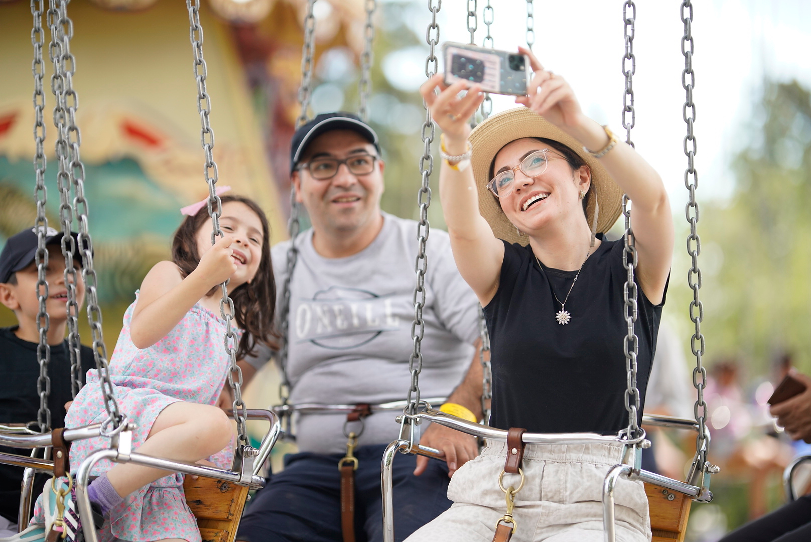 Family takes a selfie on the dangler swings at Heritage Park's Historical Village in Calgary