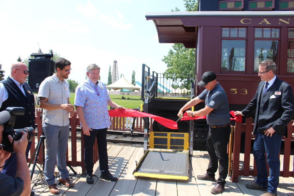 A representative from CPKC cutting the ceremonial red ribbon at the accessible railcar event