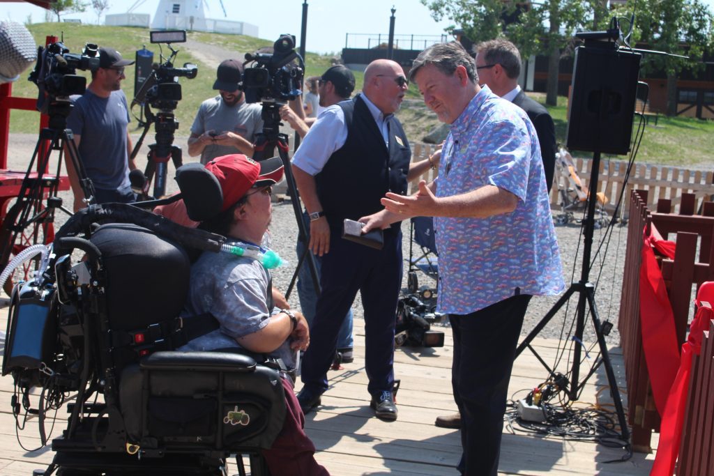 President and CEO of Heritage Park, Lindsey Galloway, chatting with Mike Jorgensen, a long-time Heritage Park visitor who requires a wheelchair.