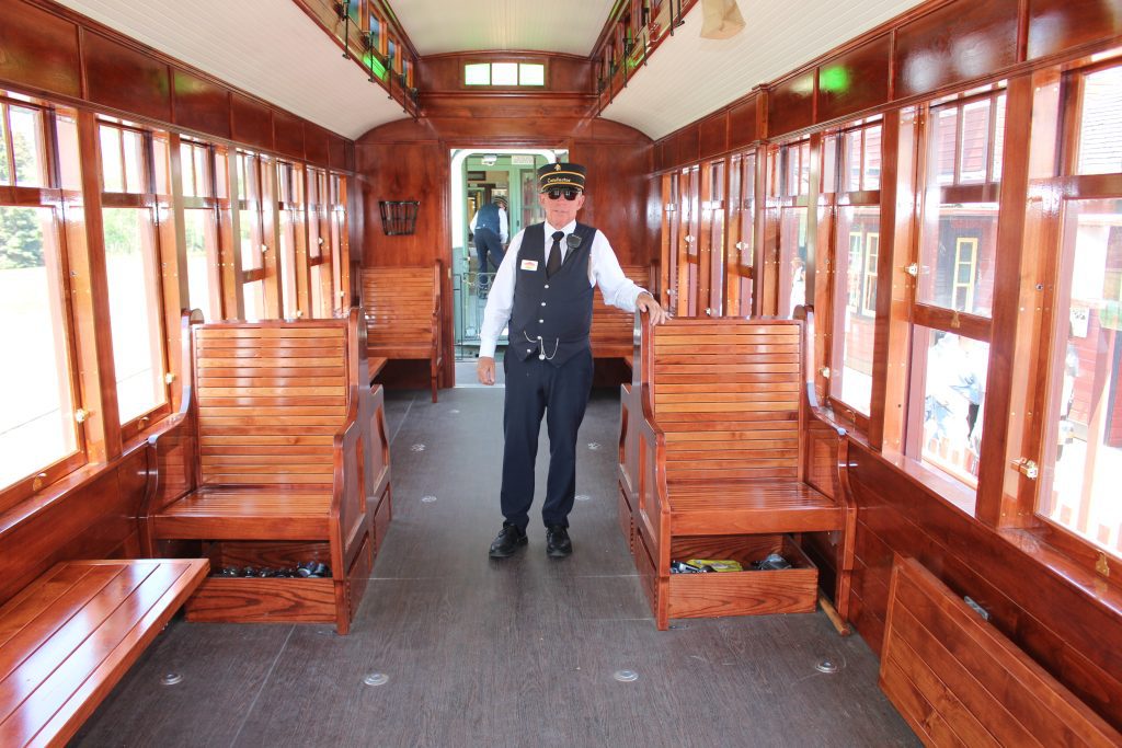 A conductor showing off the inside of Heritage Park's brand new accessible railcar