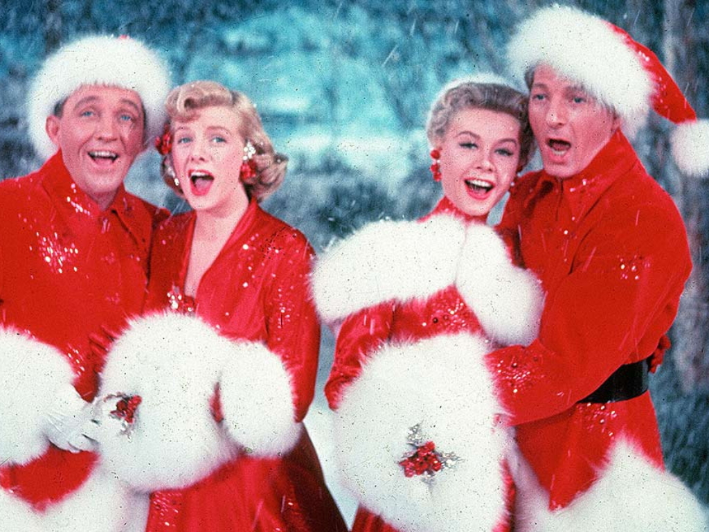 Two men and two women wearing santa outfits singing.