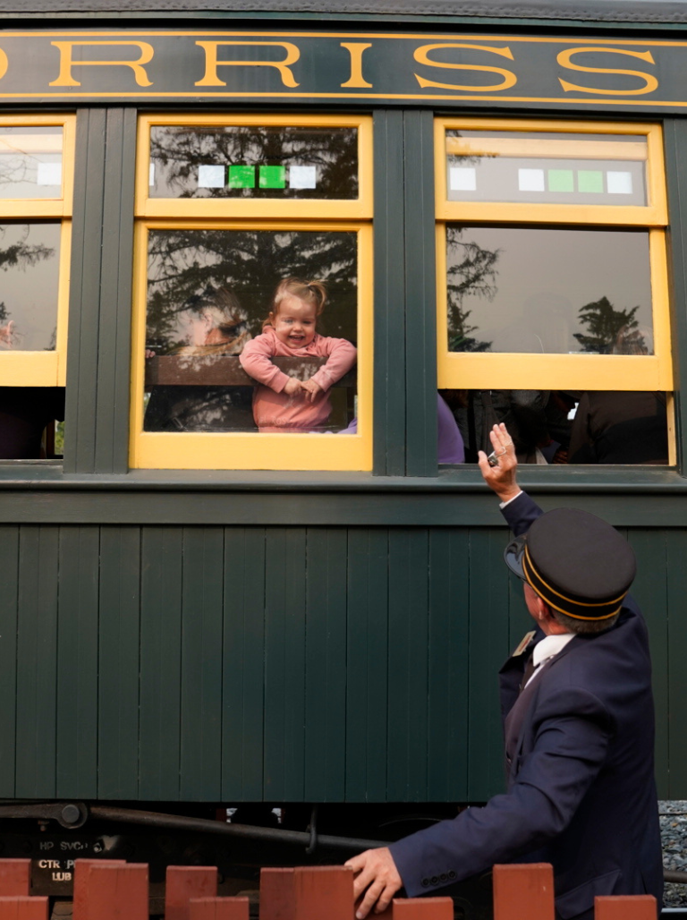 Conductor waves to little girl on the steam train at Calgary's Heritage Park